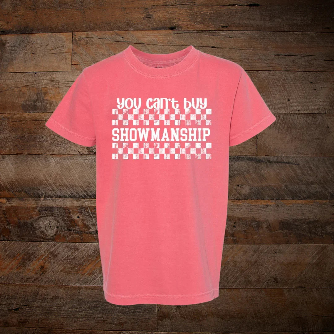 Pink t-shirt with checkered graphic and 'You can't buy showmanship' text on wood background