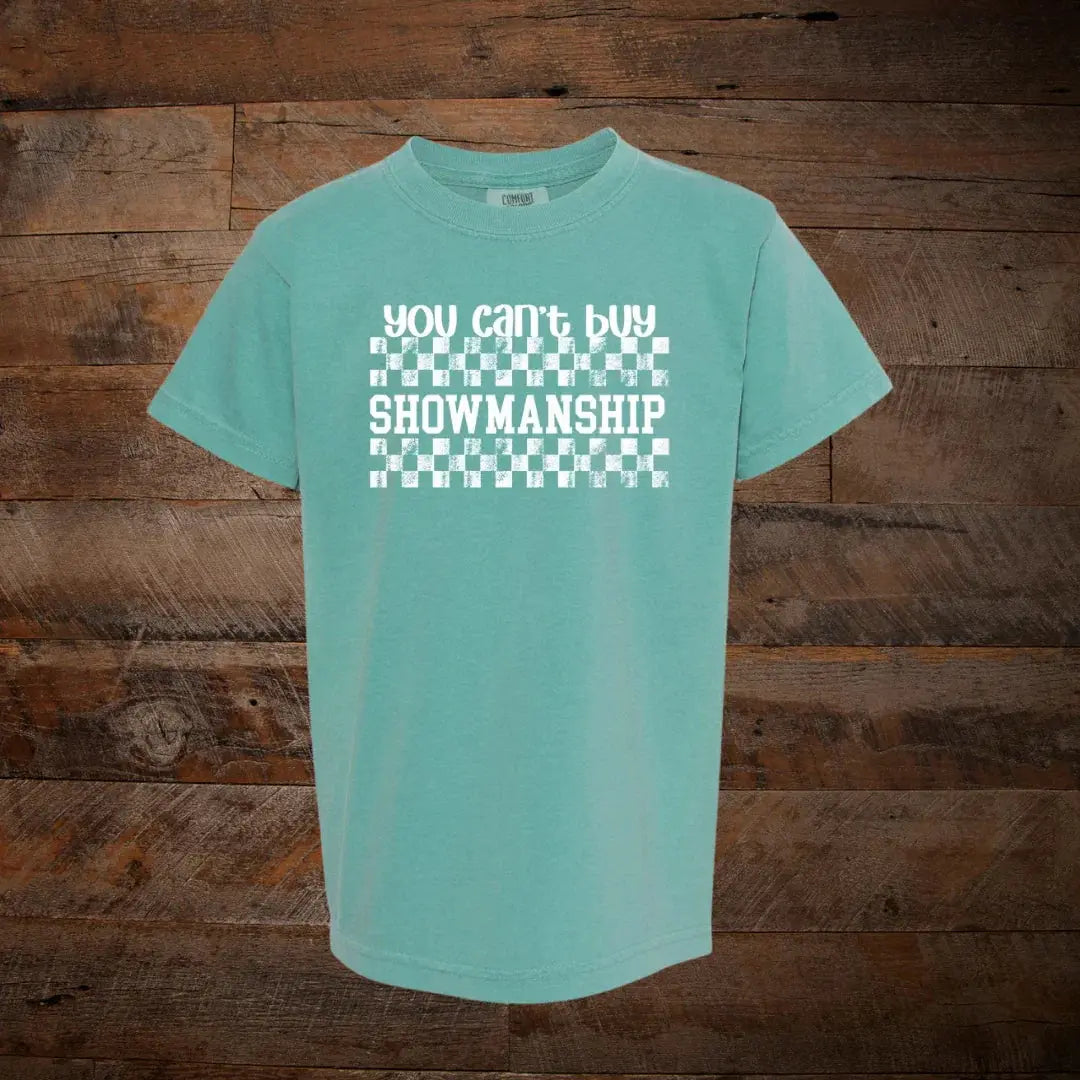Teal t-shirt with white checkered design and 'You can't buy SHOWMANSHIP' text, rustic wood background