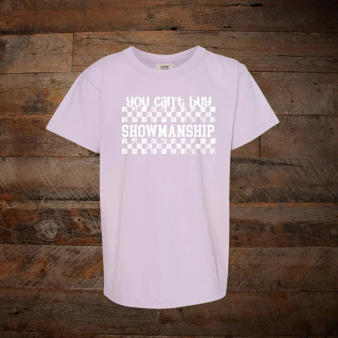 Light purple t-shirt with 'you can't buy showmanship' text and checkerboard design on wood background