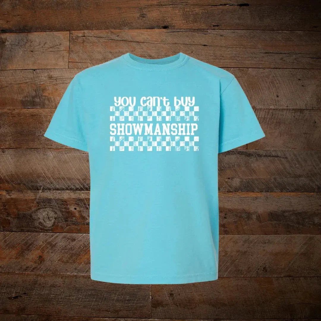 Light blue unisex t-shirt with white checkered 'You can't buy showmanship' text on wood background