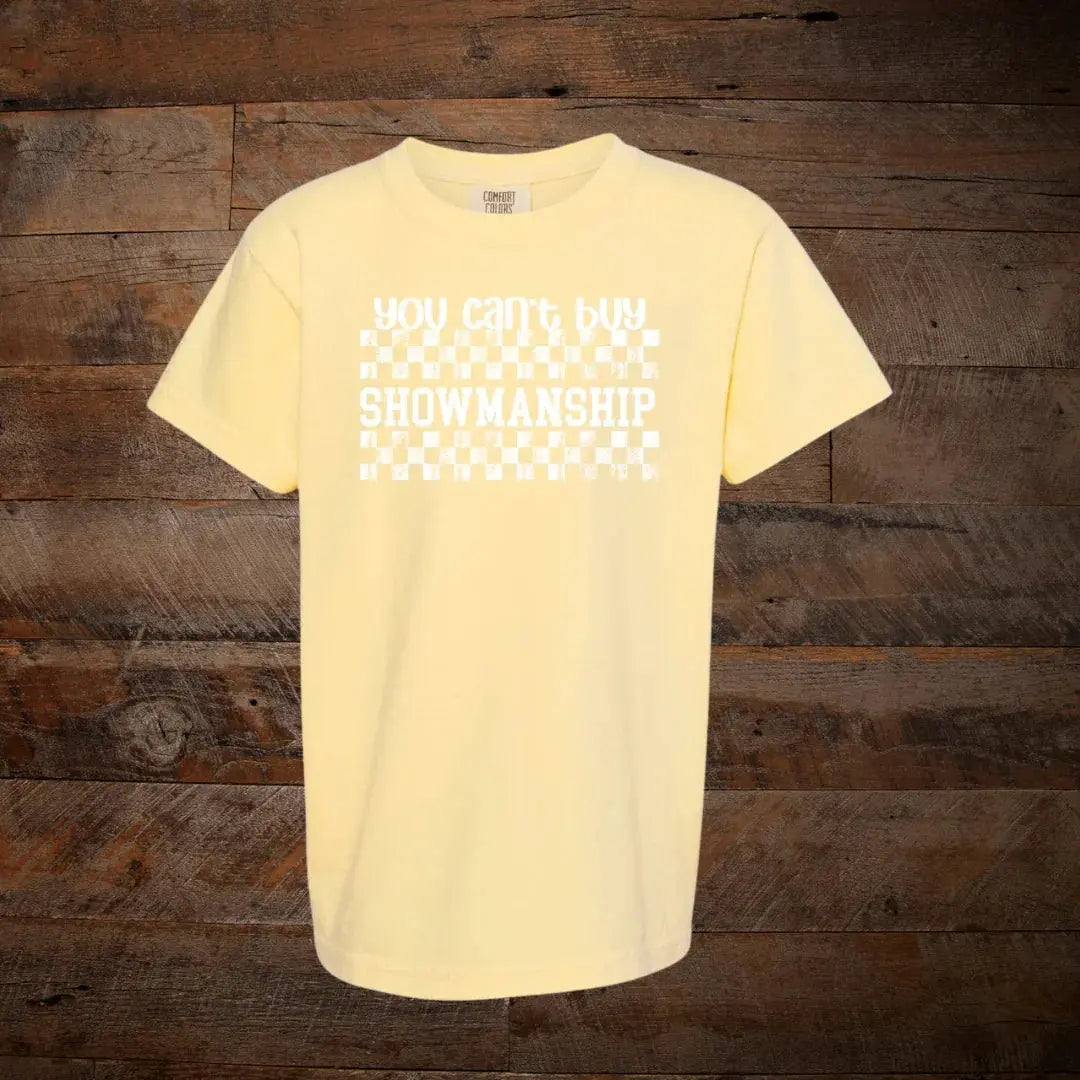 Yellow t-shirt with 'You can't buy showmanship' text and checkerboard graphic on wood background