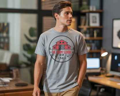 Man wearing grey T-shirt with red barn and 'The Farm School Co-op' logo in modern office